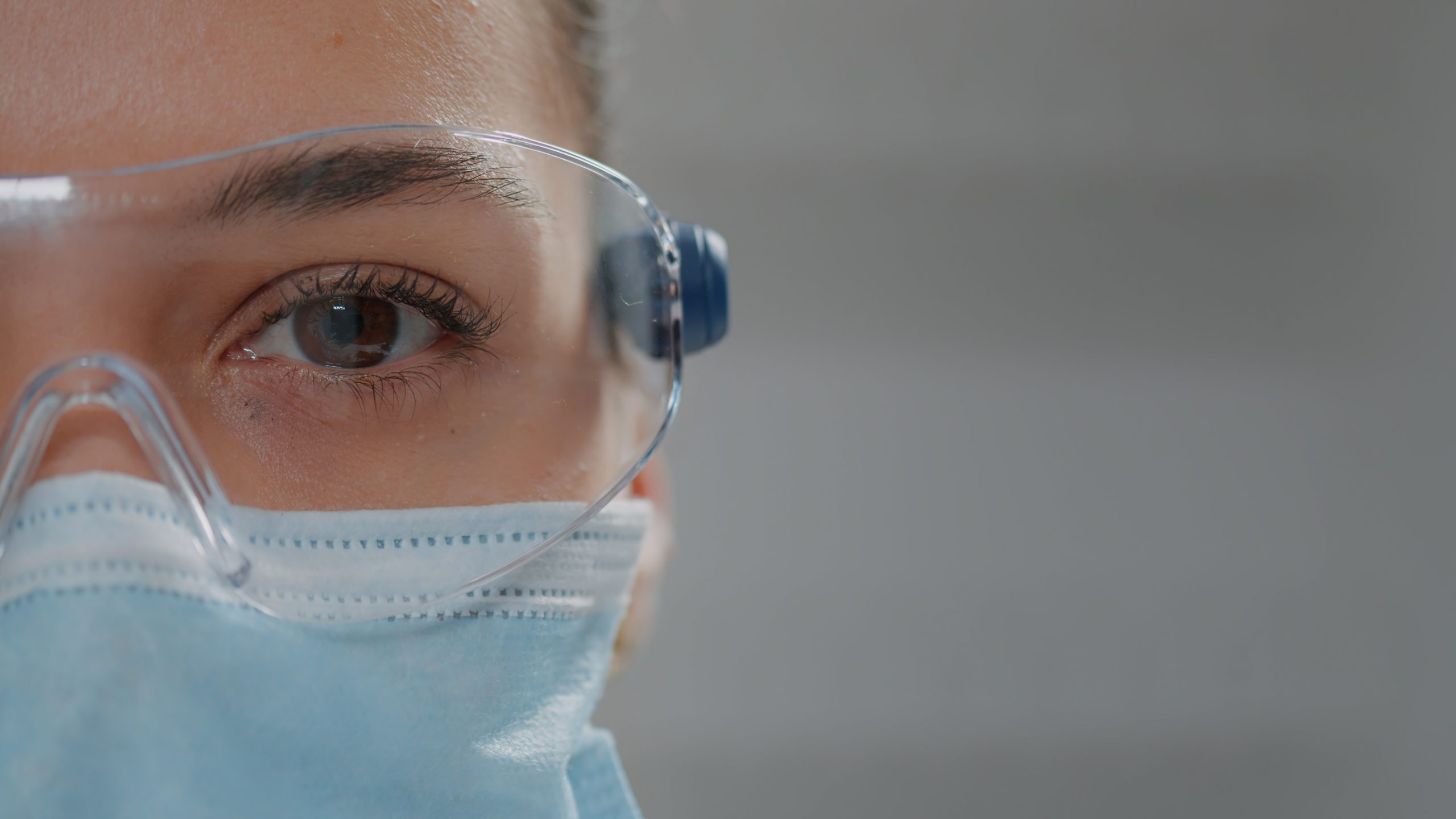 Close-up of hald woman's face with safety goggles and mask on.